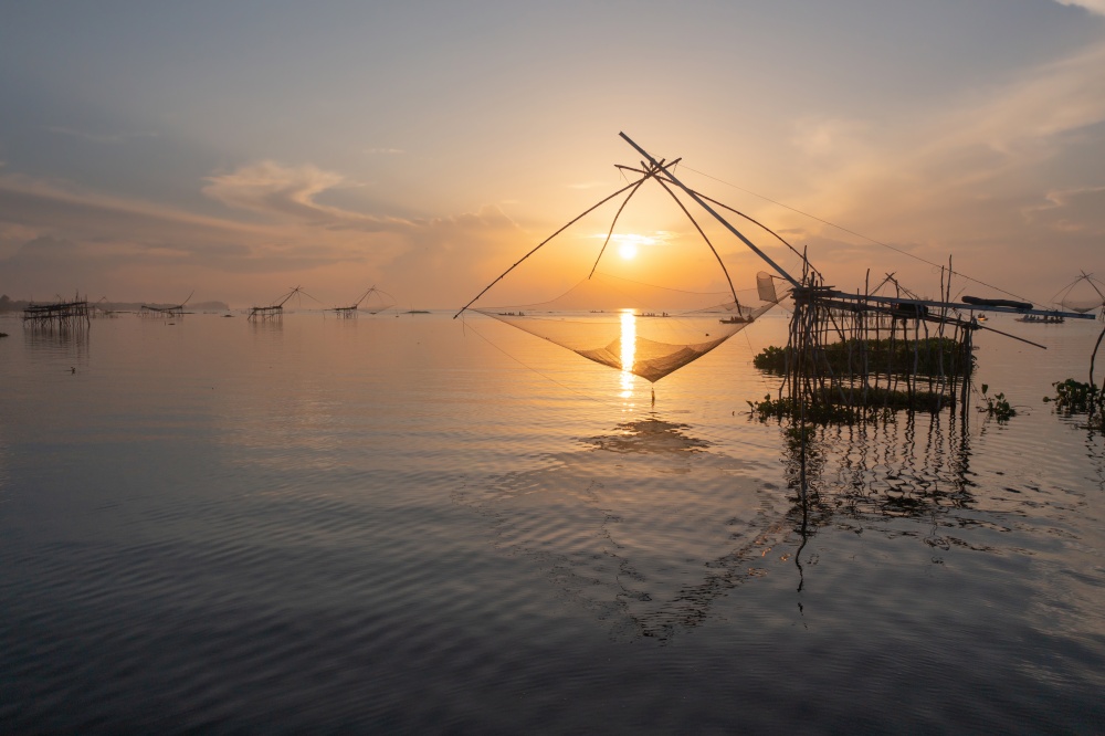 Local fishing trap net in canel, lake or river at sunset. Nature landscape fisheries and fishing tools lifestyle at Pak Pha, Phattalung, Thailand. Aquaculture farming.