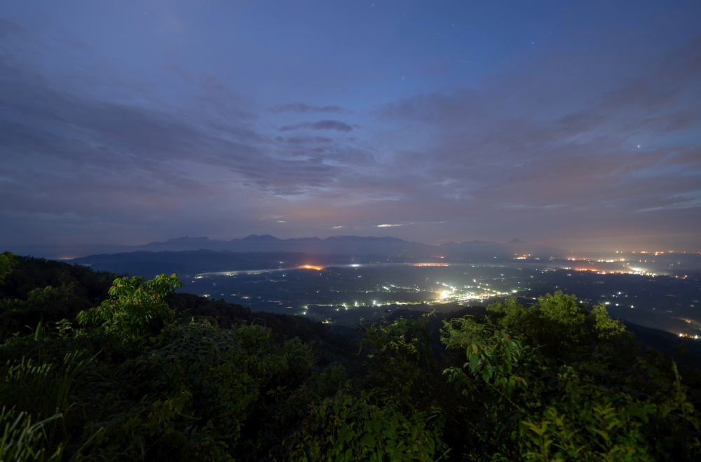 Aerial top view of forest trees with fog mist and green mountain hill at night. Nature landscape background, Thailand.