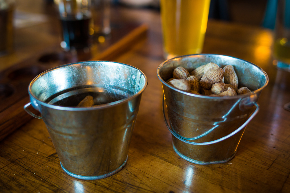 Bar buckets with raw peanuts and beer on the background. Bar buckets with raw peanuts and beer