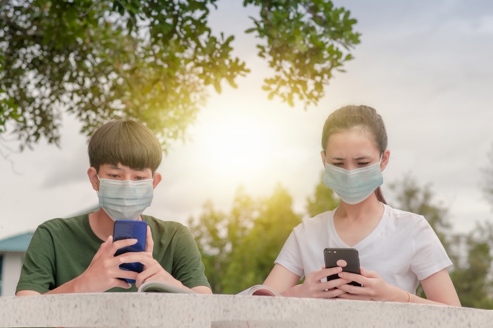 Boy and Girl in face mask new normal using mobile smart phone keep social distancing protect coronavirus covid 19