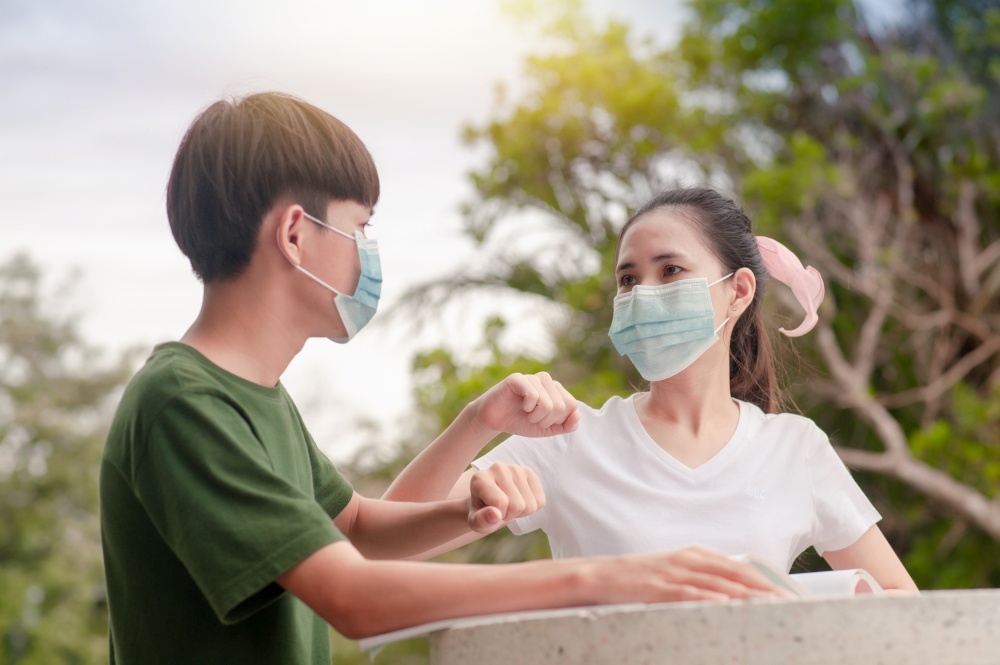 Boy and Girl in face mask new normal shake hand elbow keep social distancing protect coronavirus covid 19