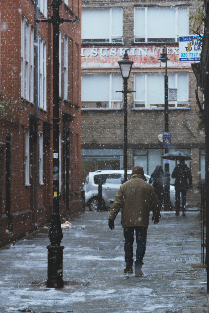 Man walking under heavy snow in London