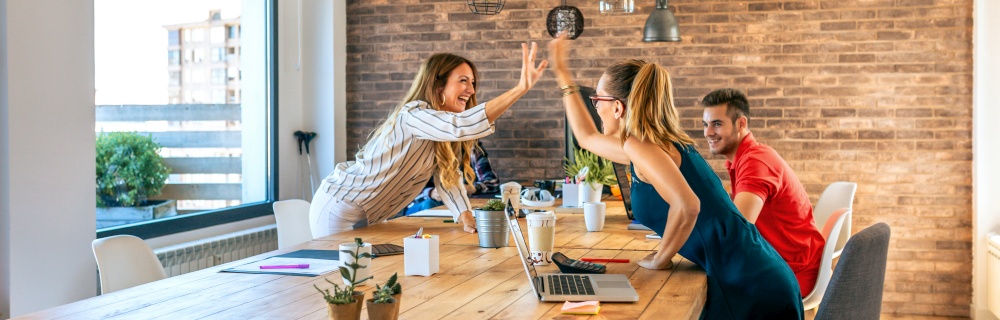 Business women celebrating a success high-fiving hands in the office