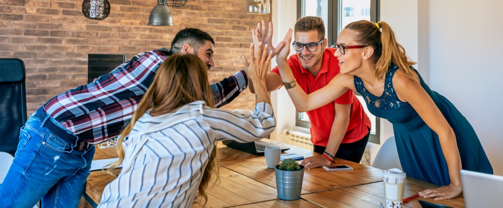 Businesspeople celebrating a success high-fiving in the office