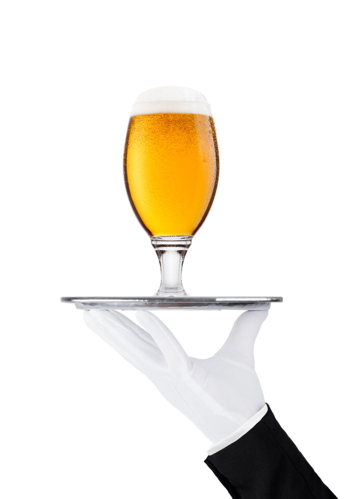 Hand with glove holds tray with lager beer glass with foam and dew isolated on white background