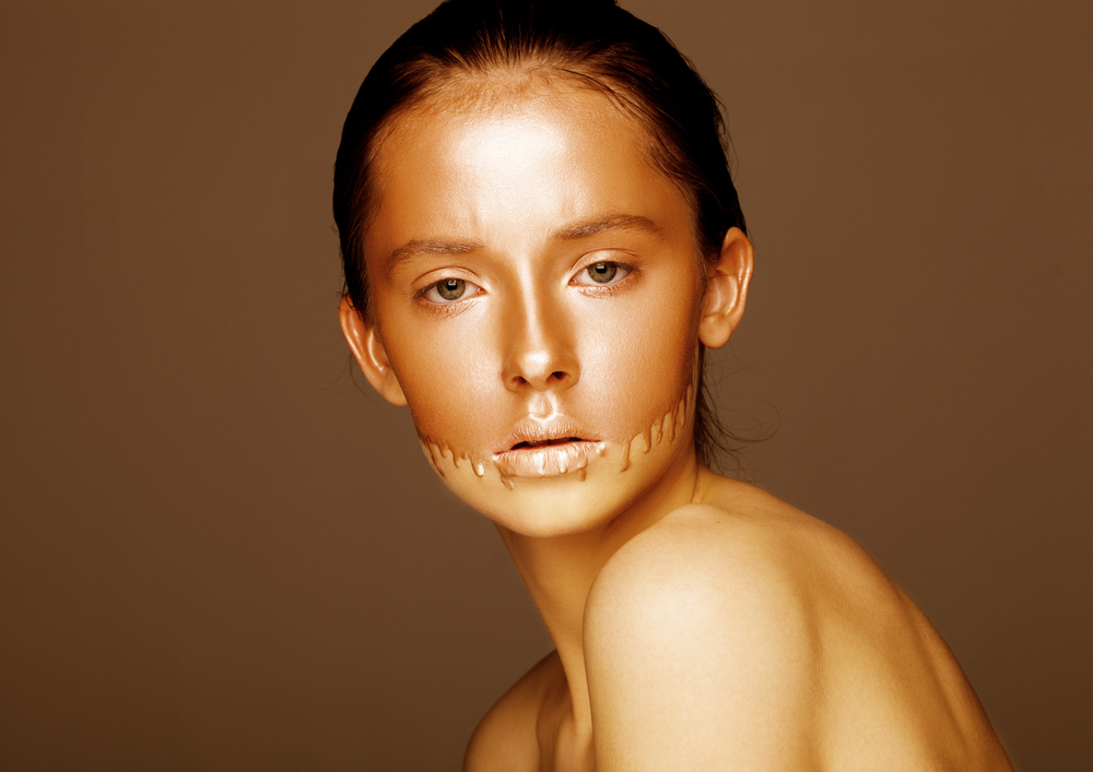 Beauty portrait with foundation makeup over face on brown background