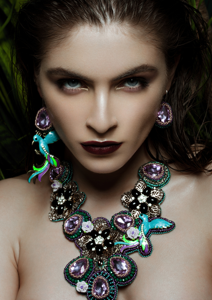 Beautiful woman wearing exotic tropical jewelry on green plants background