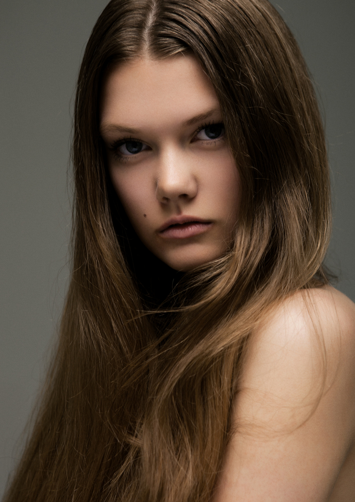 Portrait of beautiful young girl with long hair on grey background