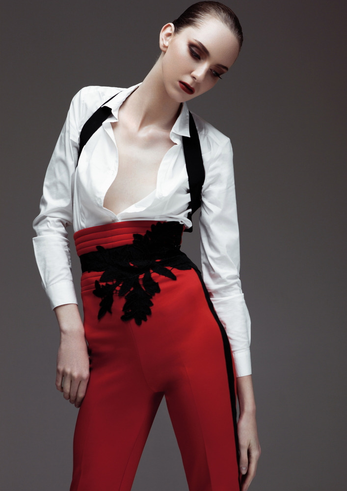 Beautiful fashion model wearing red pants and white shirt on grey background