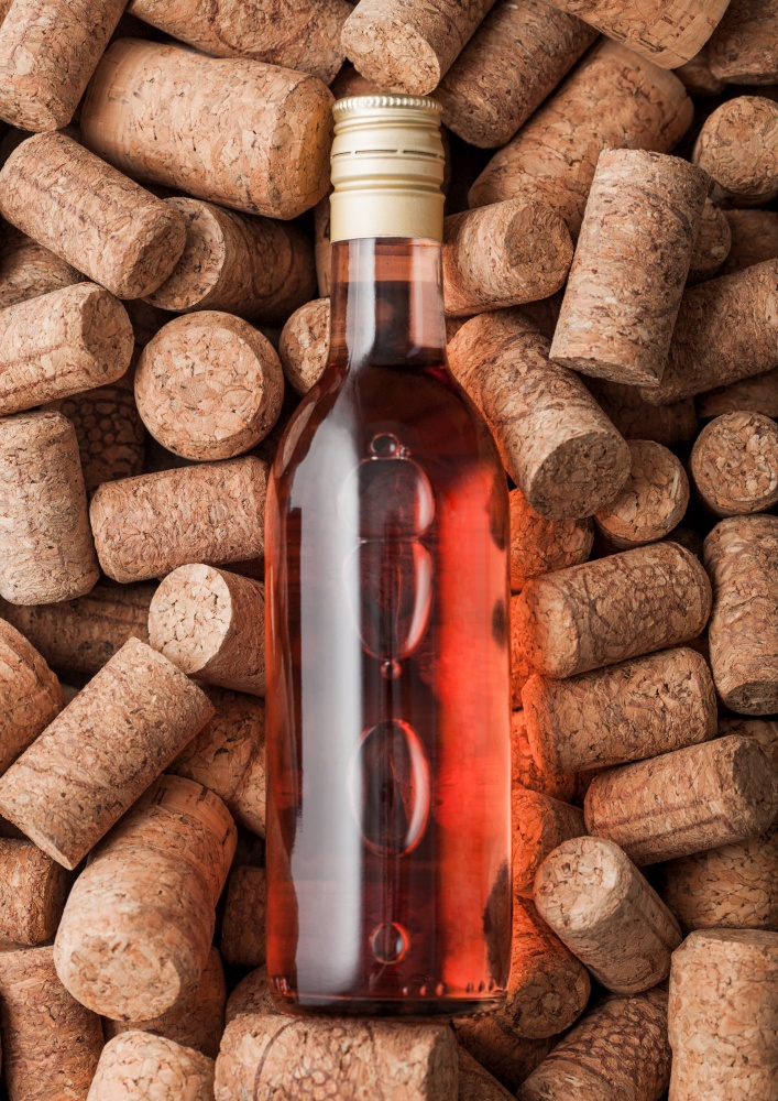 Bottle of pink rose wine on top of various wine corks background. Macro