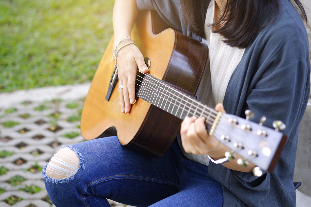 women playing acoustic guitar in the garden