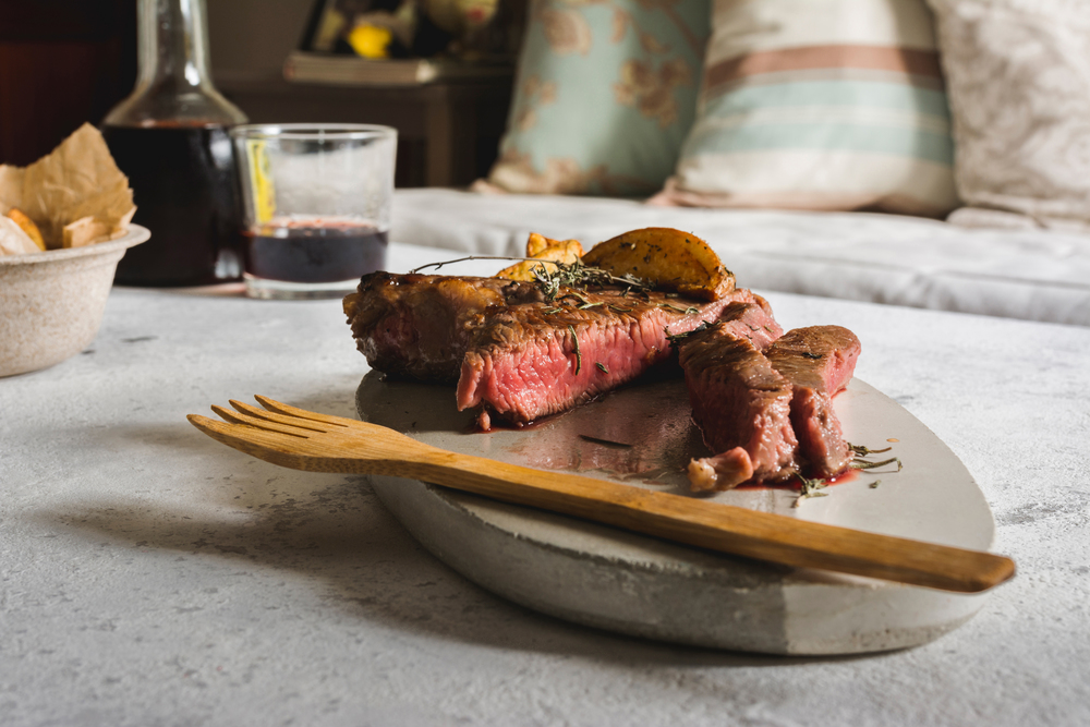 Barbecued steak on cutting board. Sealed with a strong, juicy and pink fire inside. with fried potato chips.. Barbecued steak on cutting board. Sealed with a strong