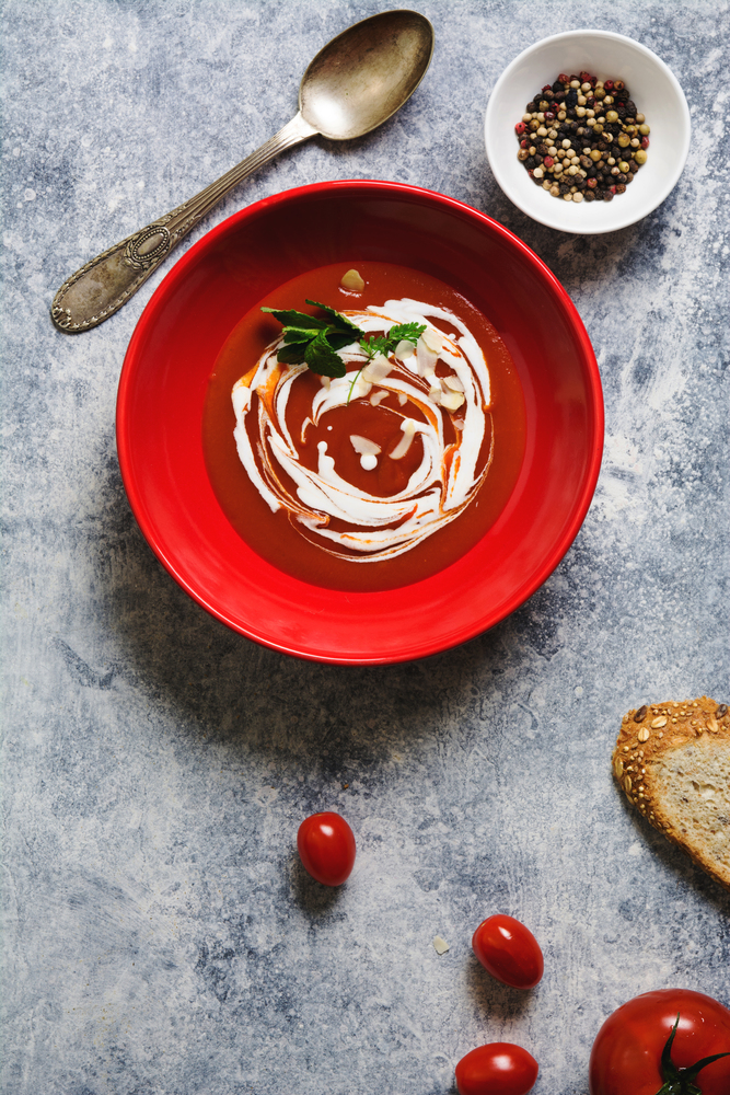 tomato cream soup in red bowl on grunge background