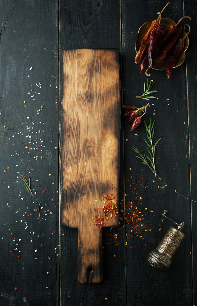 Cutting wooden board with spices on a dark background