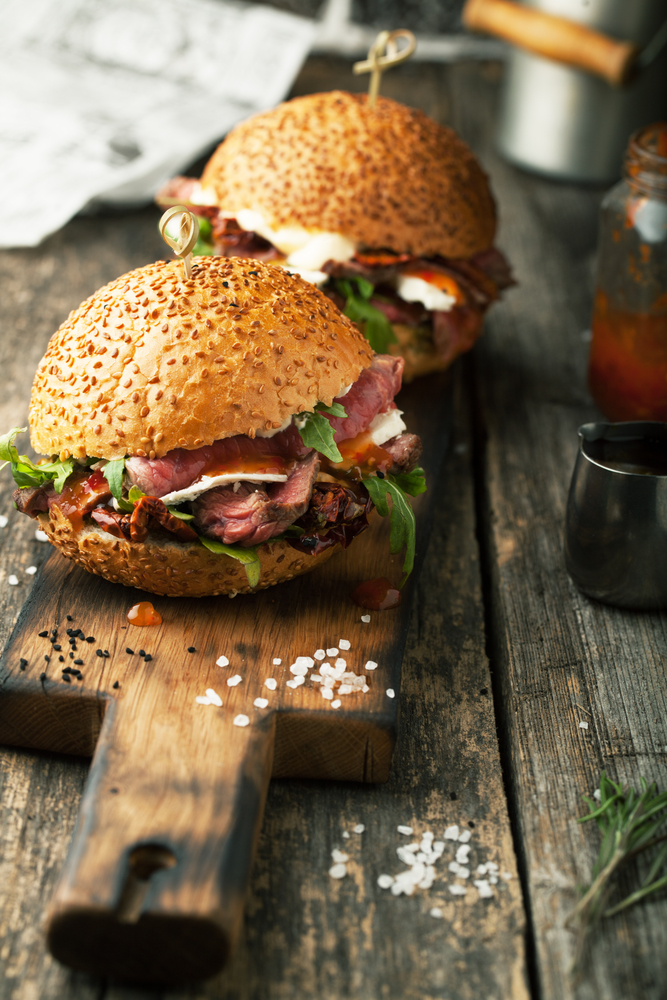 Delicious hamburger with beef with sauce and goat cheese on a wooden background