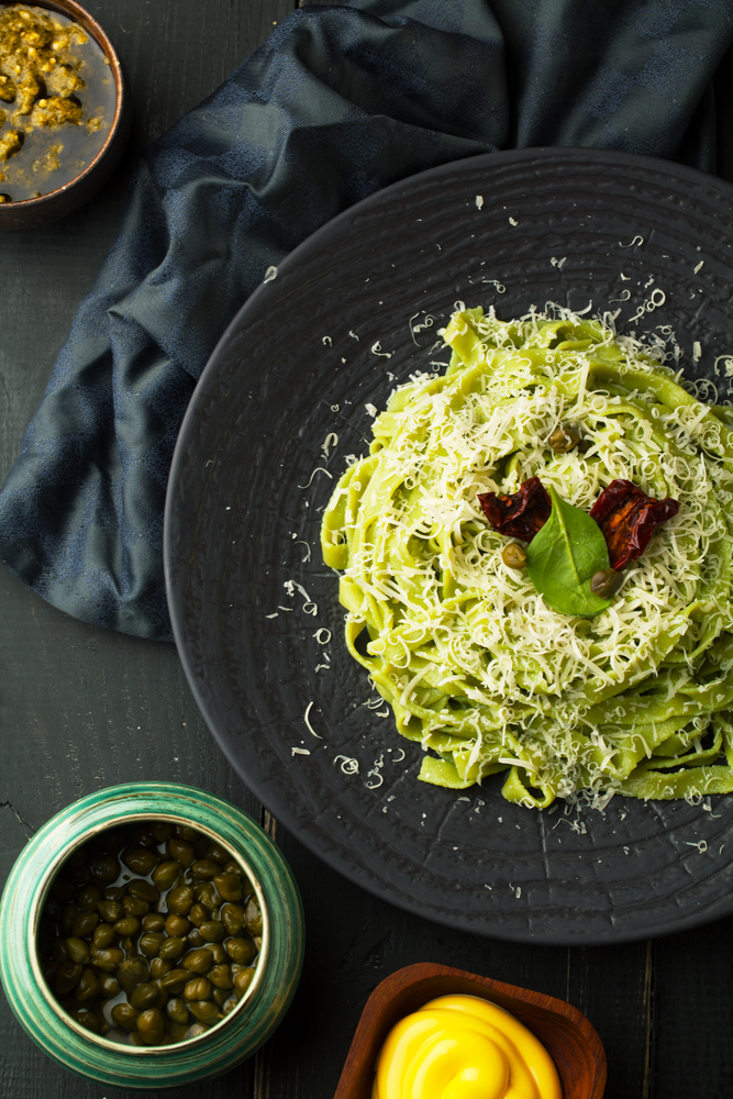 Paste with pesto and Parmesan cheese on a plate on a dark background