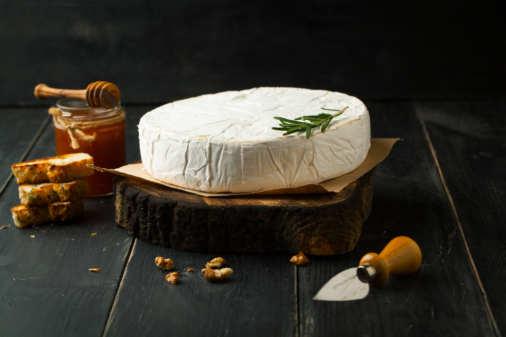 Cheese brie with honey and rosemary on a dark background