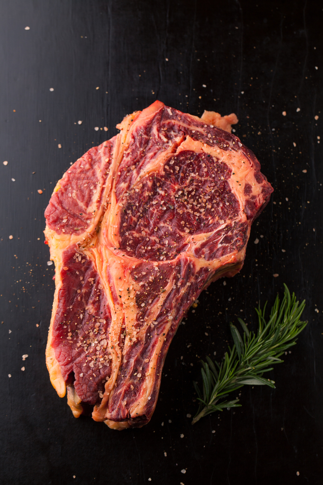 Raw fresh meat Ribeye Steak with  pepper and salt on wooden background
