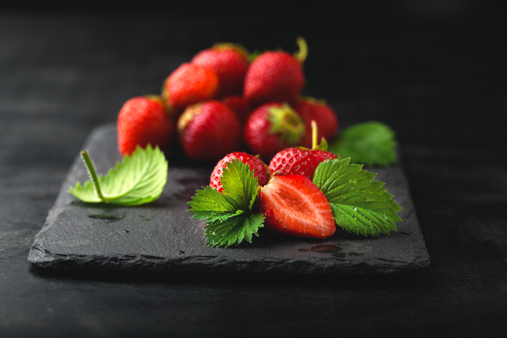 Ripe strawberry with a leaf on a dark background