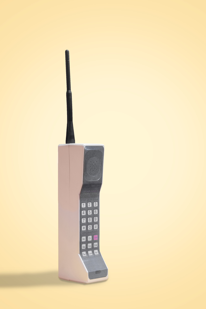 Retro mobile cellular phone on a vintage yellow background with copy space and room for text