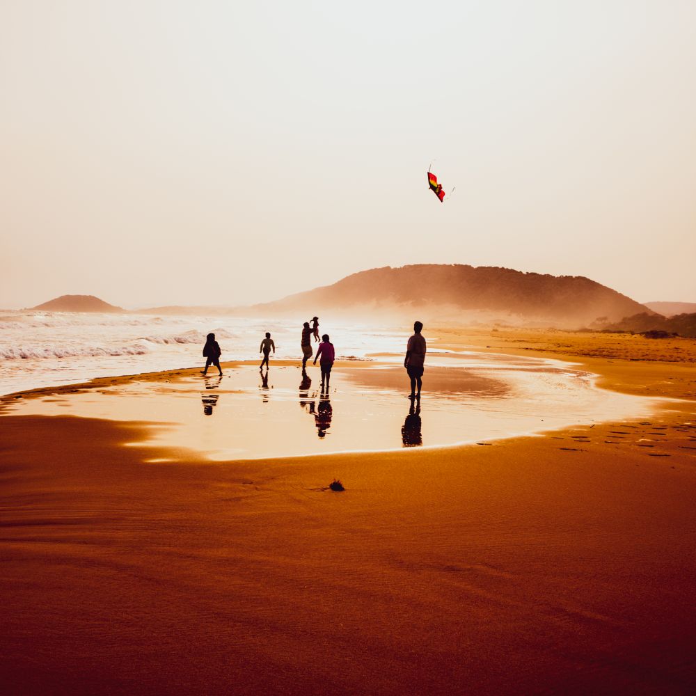 Atmospheric capture of silhouettes of people playing and flying a kite in beautiful sandy Golden Beach in Karpasia, Cyprus