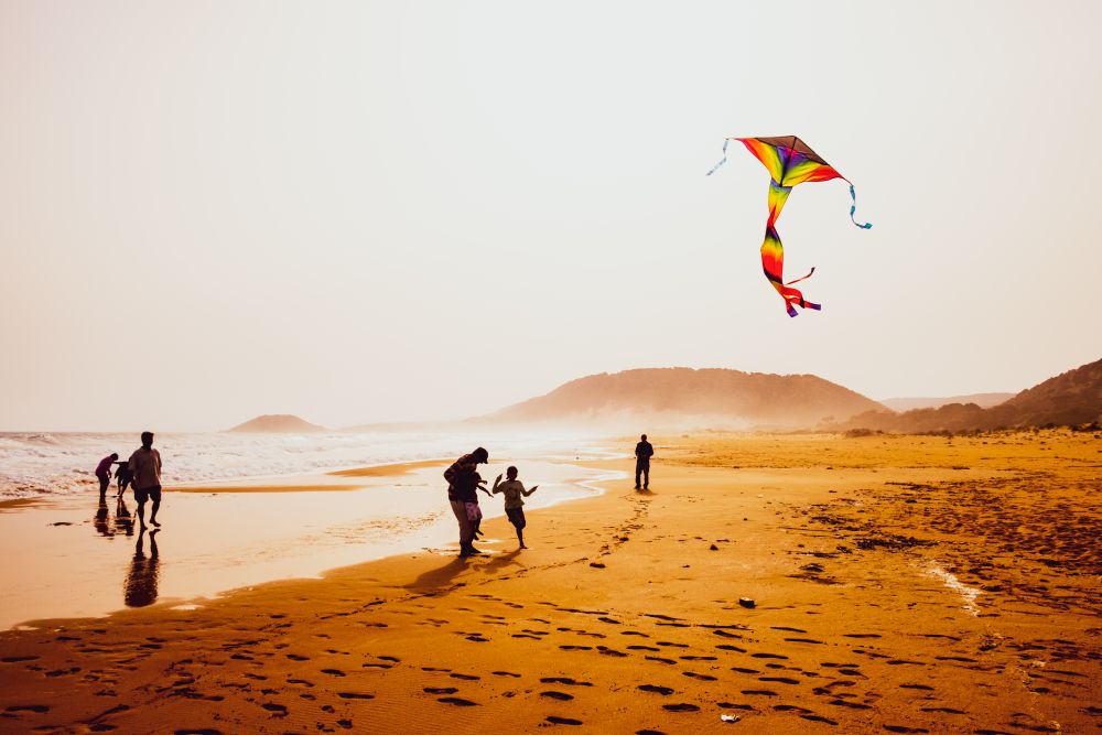 Atmospheric capture of silhouettes of people playing and flying a kite in beautiful sandy Golden Beach in Karpasia, Cyprus