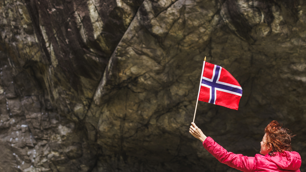 Tourist woman with norwegian flag in rocky stone mountains.. Tourist woman with norwegian flag in rocks mountains
