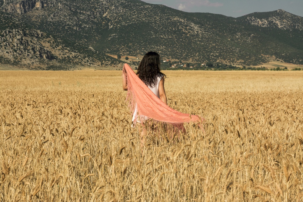 A woman in a scarf walking through a barley field in Antalya