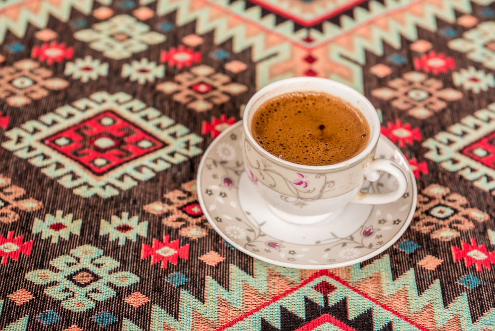 Top view of Traditional Turkish coffee cooked on embers is served in a cup on a traditional Turkish rug.. Traditional Turkish coffee on a traditional Turkish rug
