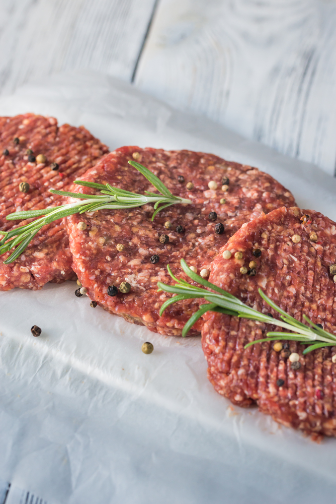 Raw beef patties on the white parchment