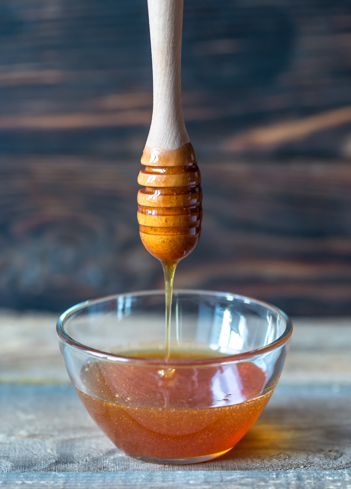 Bowl of honey on the dark wooden background