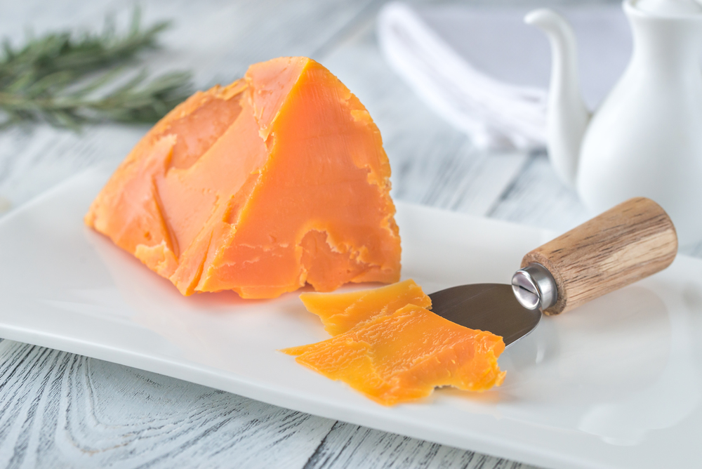 Wedge of Mimolette cheese on white plate