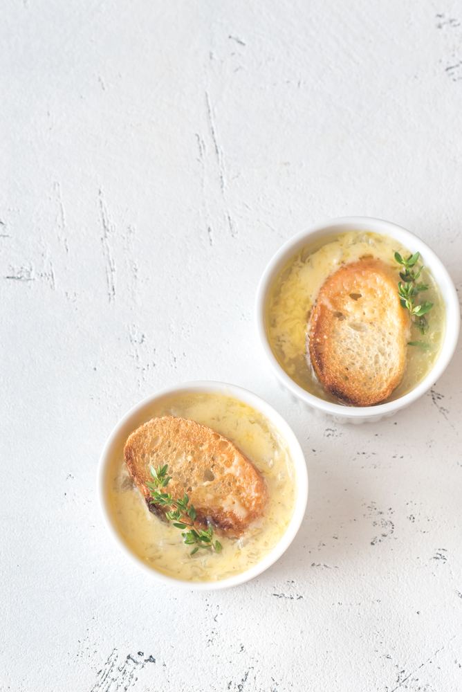 Two bowls of onion soup with fresh thyme on the table