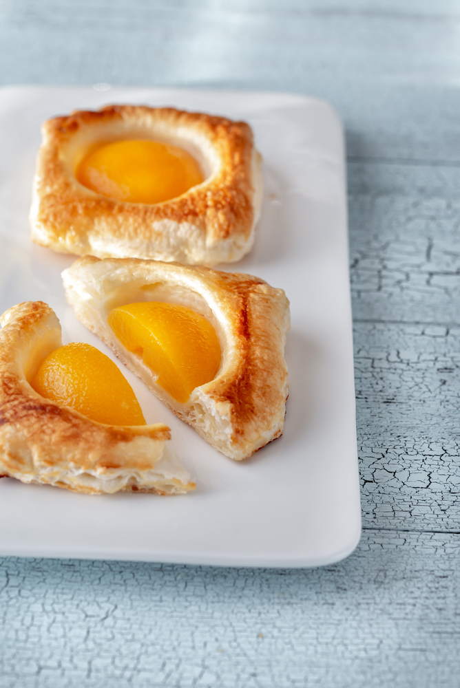 Puff pastry with canned peaches on the wooden table