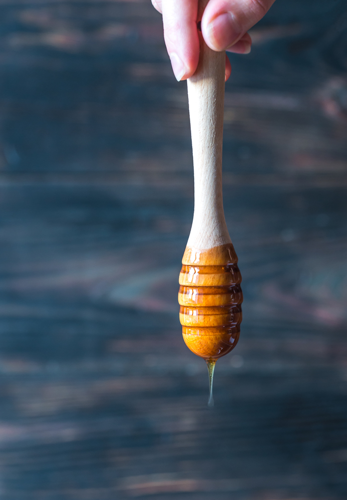 Pouring honey on the dark wooden background