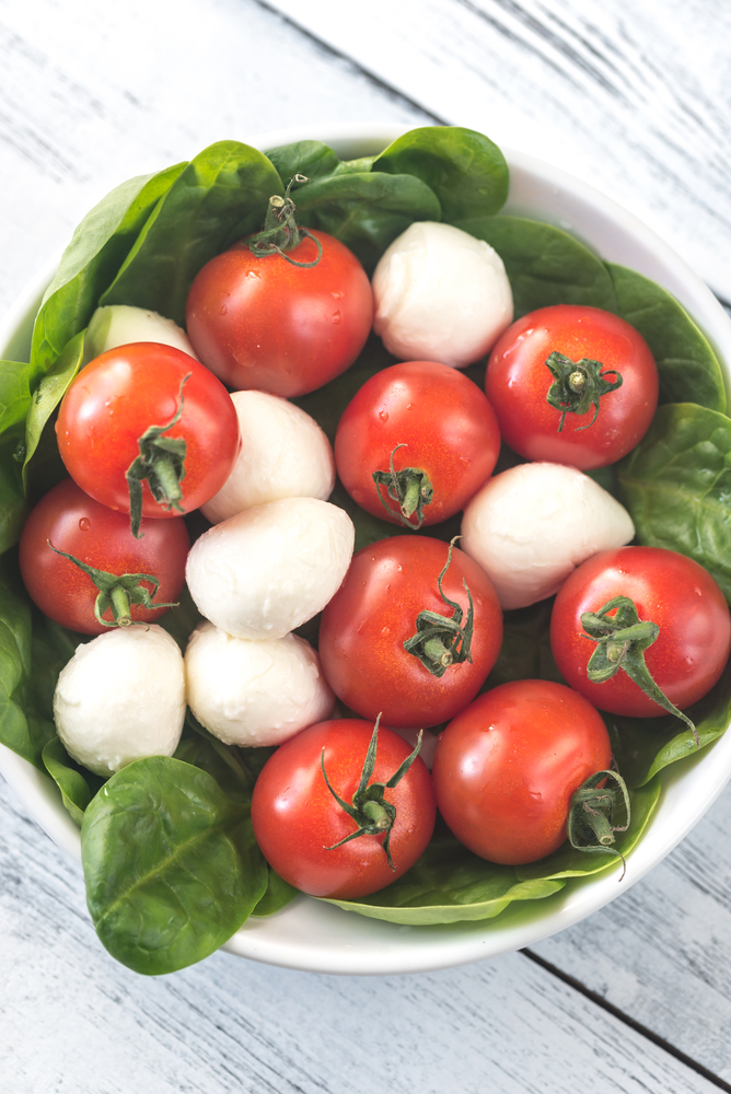 Fresh cherry tomatoes with mozzarella and spinach leaves