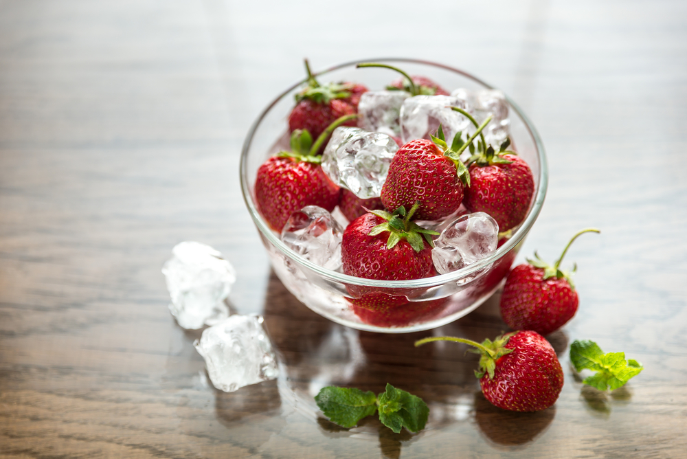 Fresh strawberries with ice cubes in the glass bowl