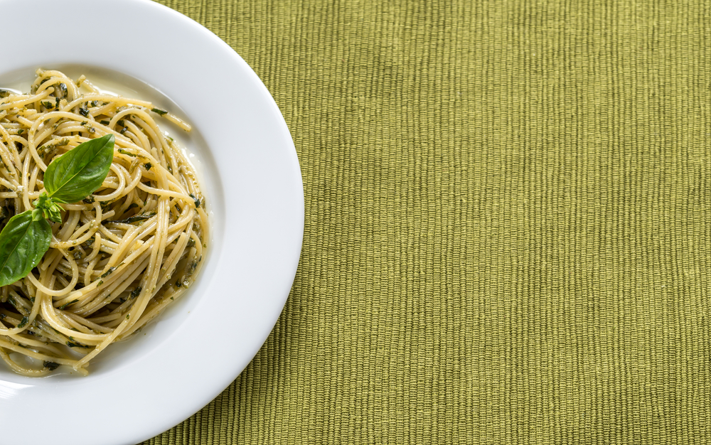 Portion of pasta with pesto sauce and basil leaf