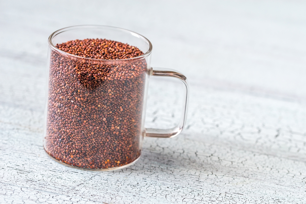 Glass mug of red quinoa on the wooden background