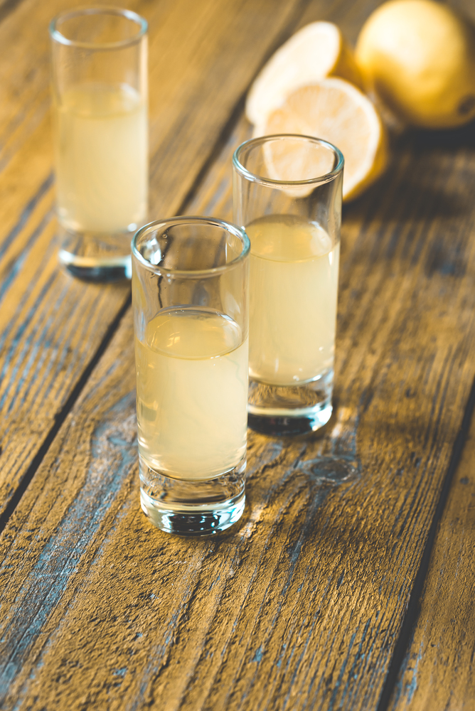Three glasses of limoncello on the wooden background