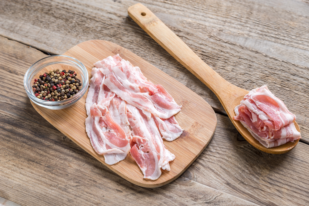 Bacon strips with pepper on wooden spoon