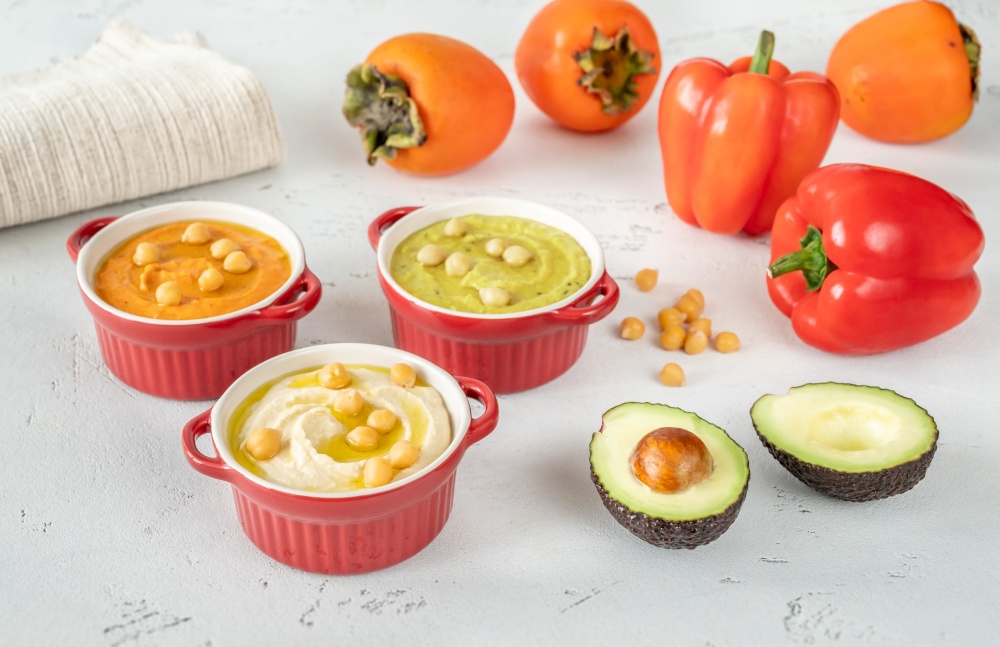 Bowls of different kinds of hummus: classic, avocado and paprika-persimmon
