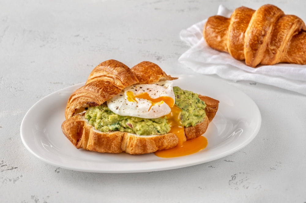 Croissant with guacamole and poached egg on the serving plate