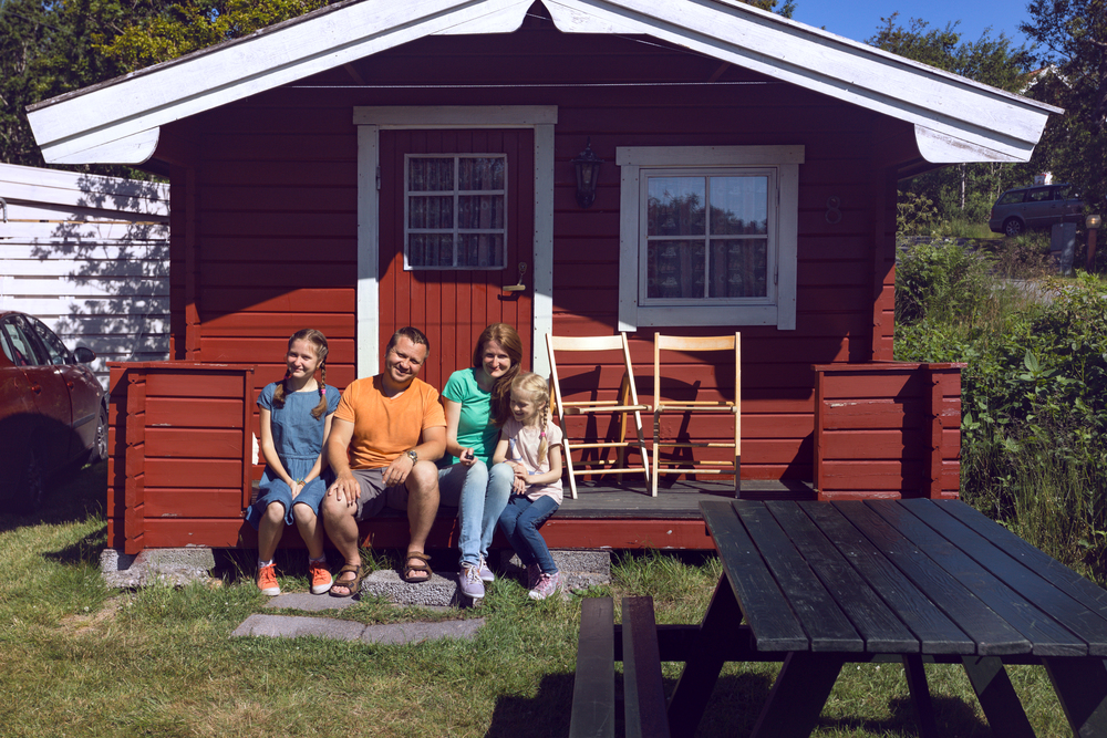 happy family -  smiling parents and their two daughters sitting near the traditional red Norwegian house, Norway