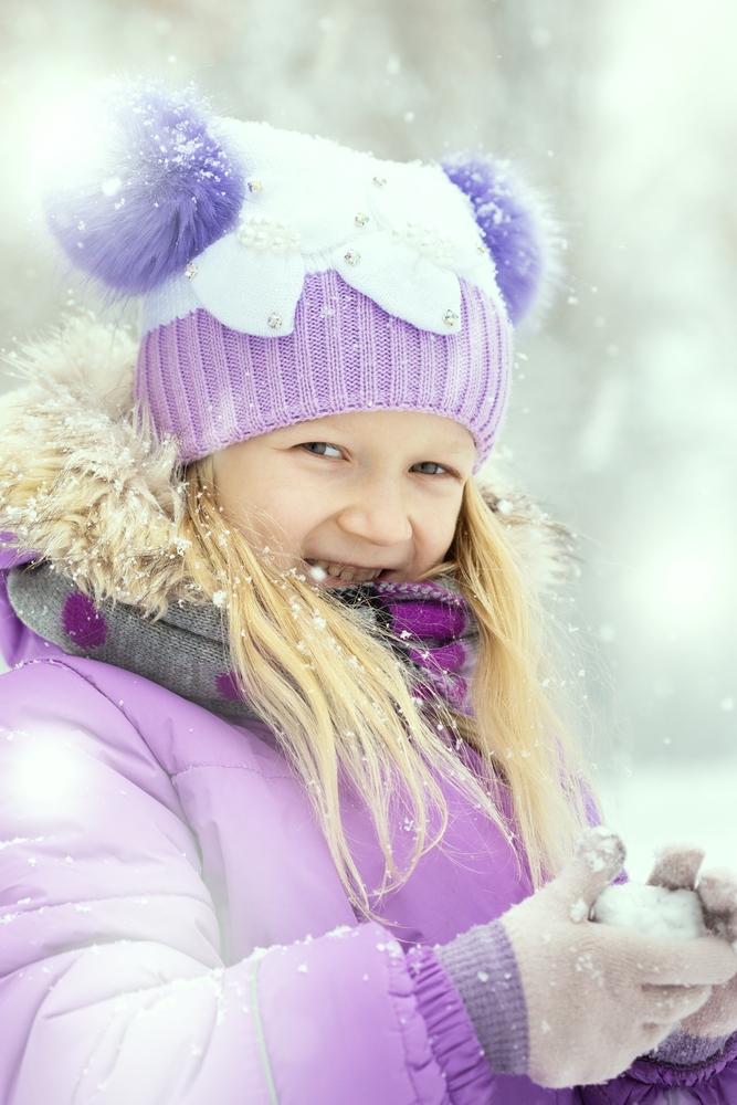 little smiling girl outdoors at the snowfall time