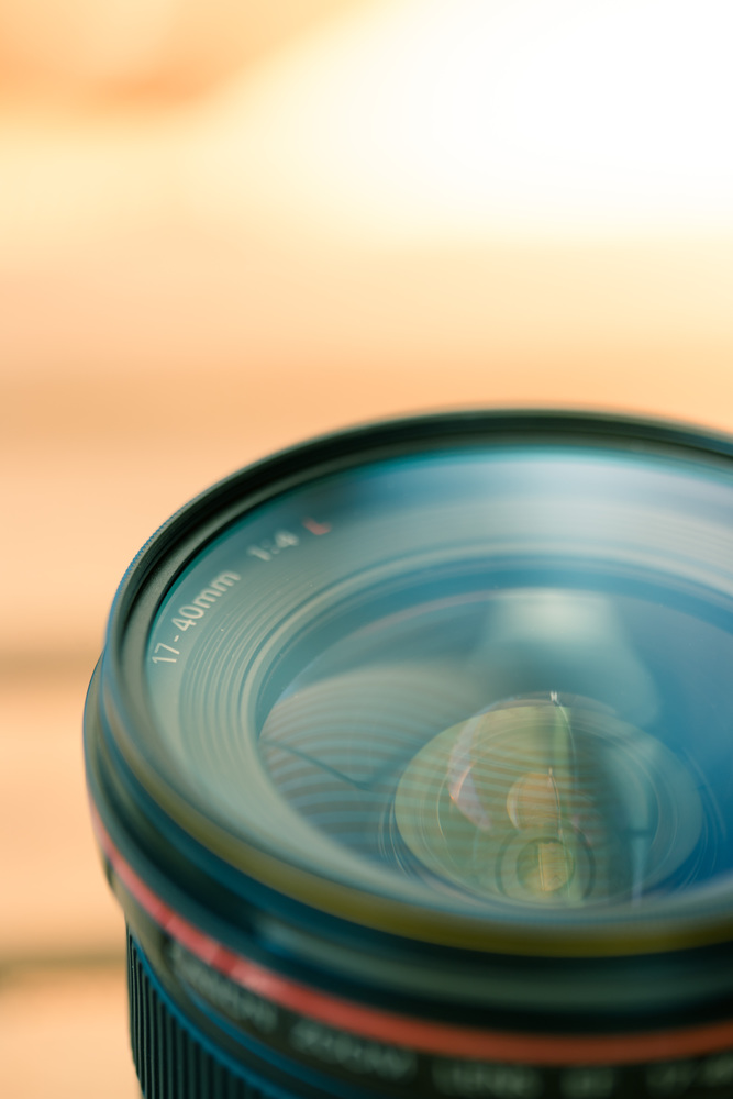 Close up picture of a professional optic photo lens. Smooth blurry background, warm colors.
