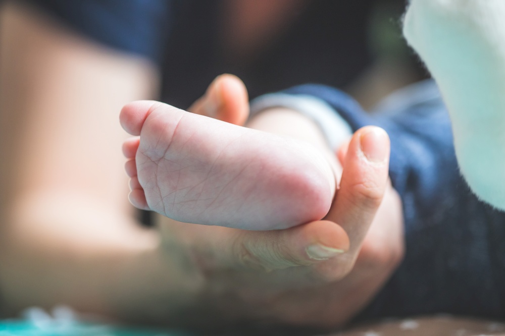 Close up of mother&rsquo;s hands, holding newborn baby feet.
