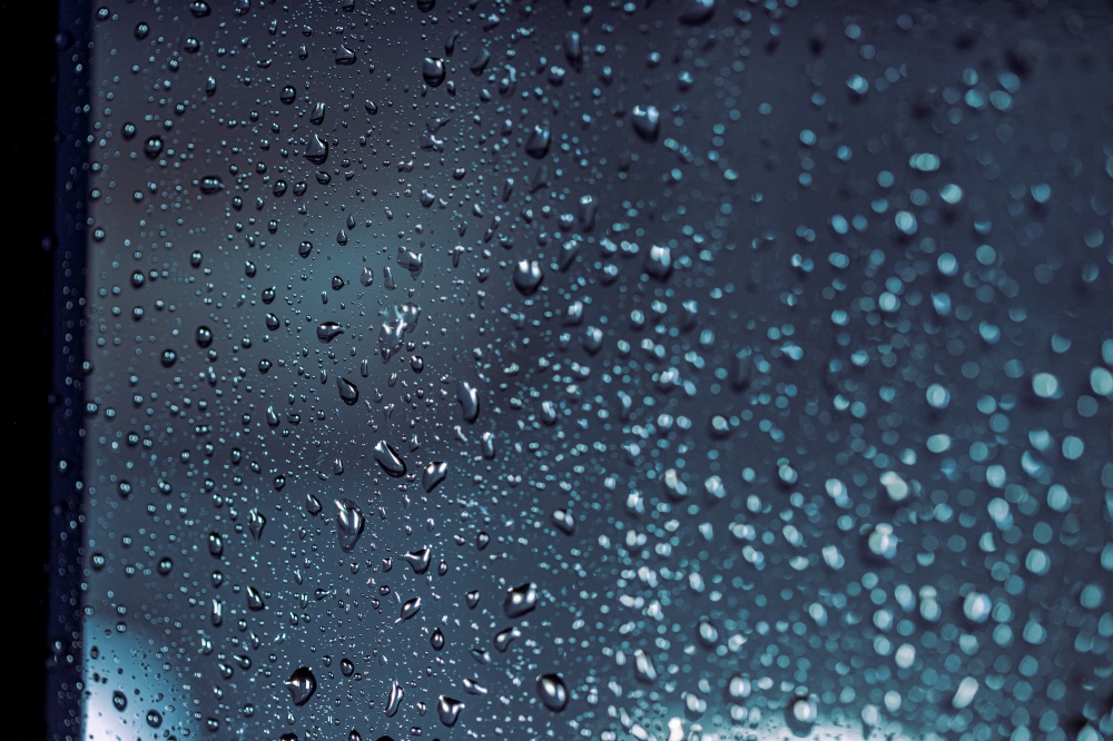 Close up of rain drops on the window in rainy night, cool lights and window frame