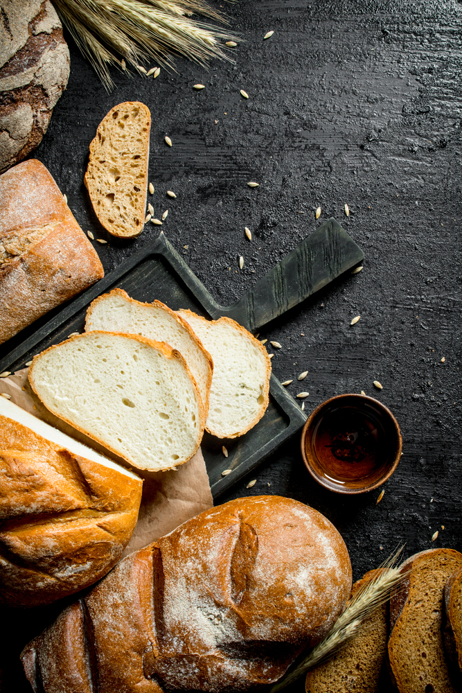 Assortment of different types of bread. On black rustic background. Assortment of different types of bread.