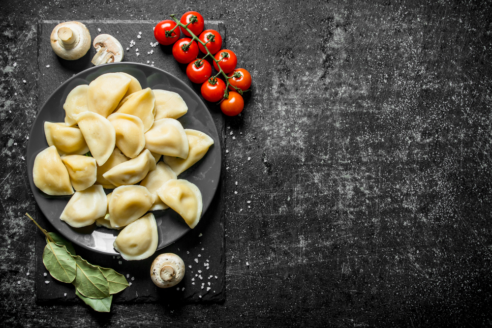Dumplings with mushrooms, tomatoes and Bay leaf. On dark rustic background. Dumplings with mushrooms, tomatoes and Bay leaf.